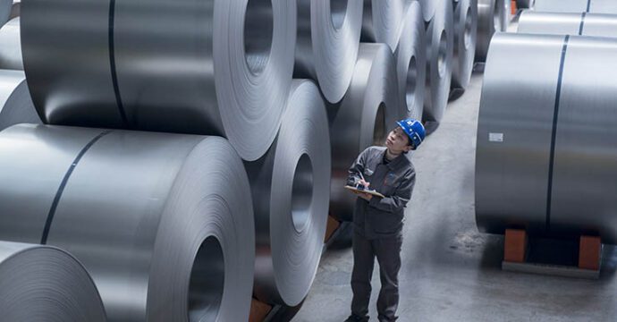 Worker inspecting cold rolled coils in storage yard. Tangsteel. Tangshan, China.
