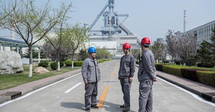 3 workers chatting with blast furnace in the background. Tangsteel, Tangshan, China.