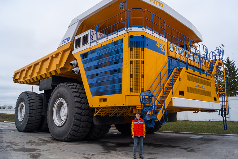 A man stands in front of a BelAZ 75710 dump truck