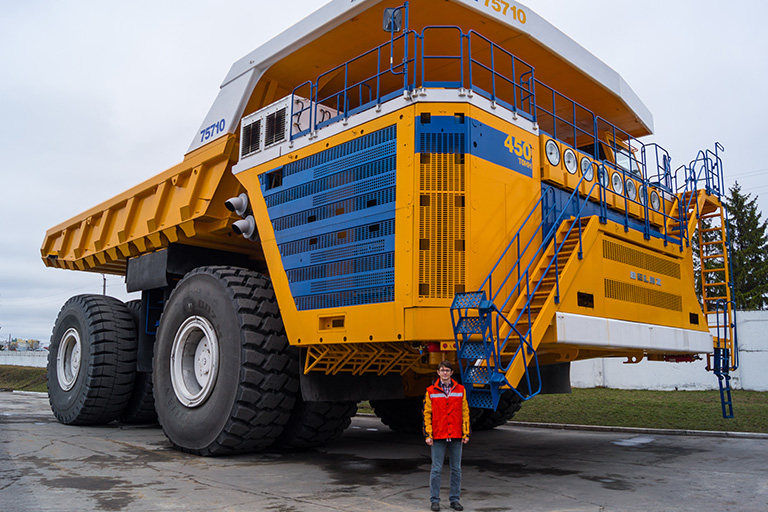 A man stands in front of a BelAZ 75710 dump truck A man stands in front of a BelAZ 75710 dump truck