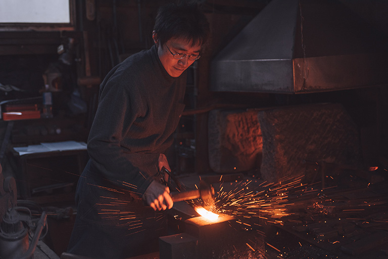 A blacksmith forging a sushi knife