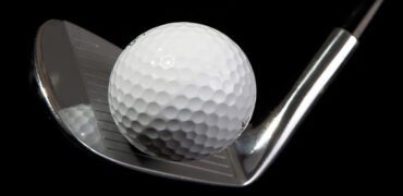 A golf club striking a ball against a black background
