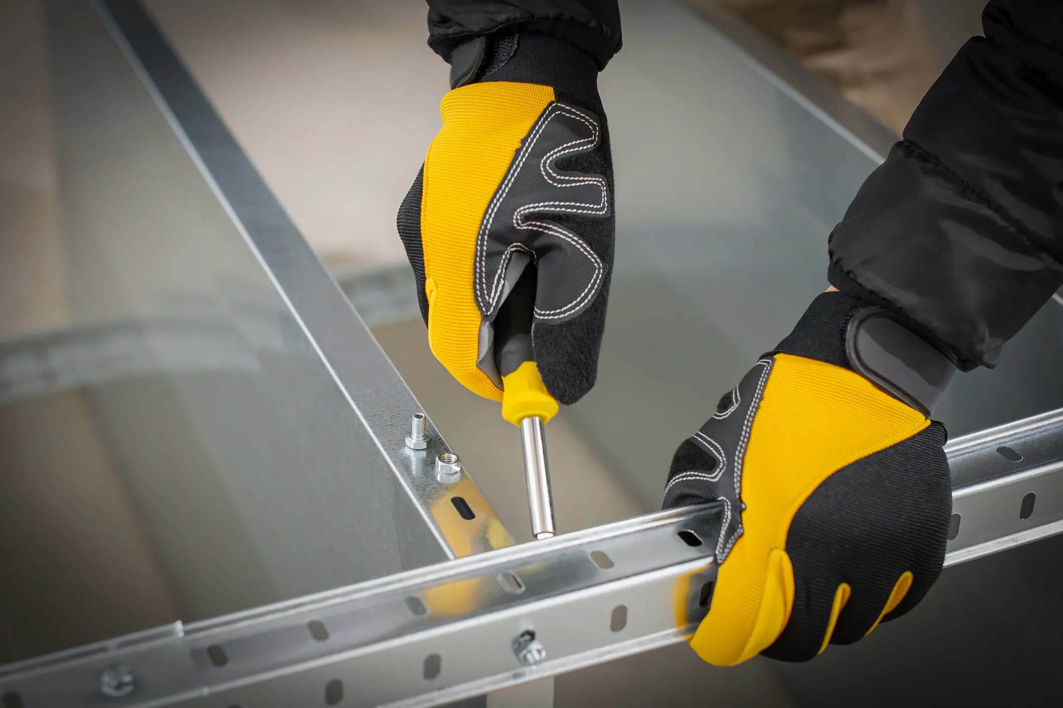 Worker hands in safety gloves mounting modular steel components with using screwdriver. Worker hands in safety gloves mounting modular steel components with using screwdriver.