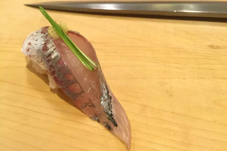 A prepared piece of sushi sits next to a knife